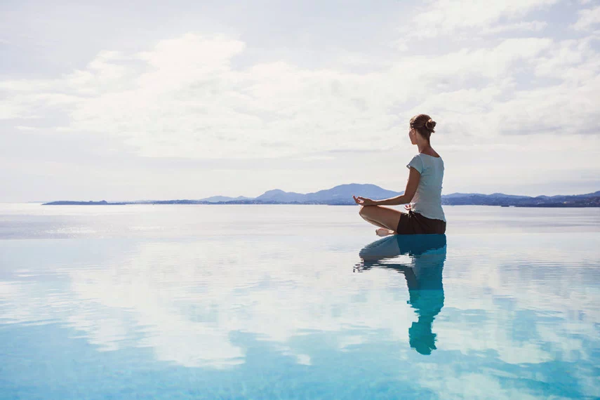 Woman meditating in the shallow water.
