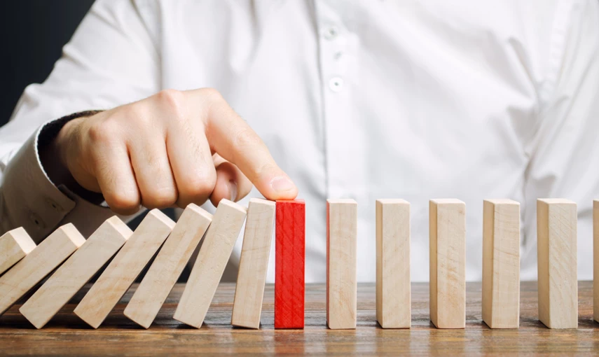A man stops the domino effect, holding the wooden piece in the middle.
